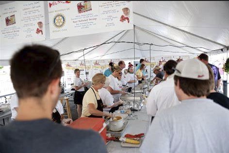 Photo of a group of people in line under a white event tent.